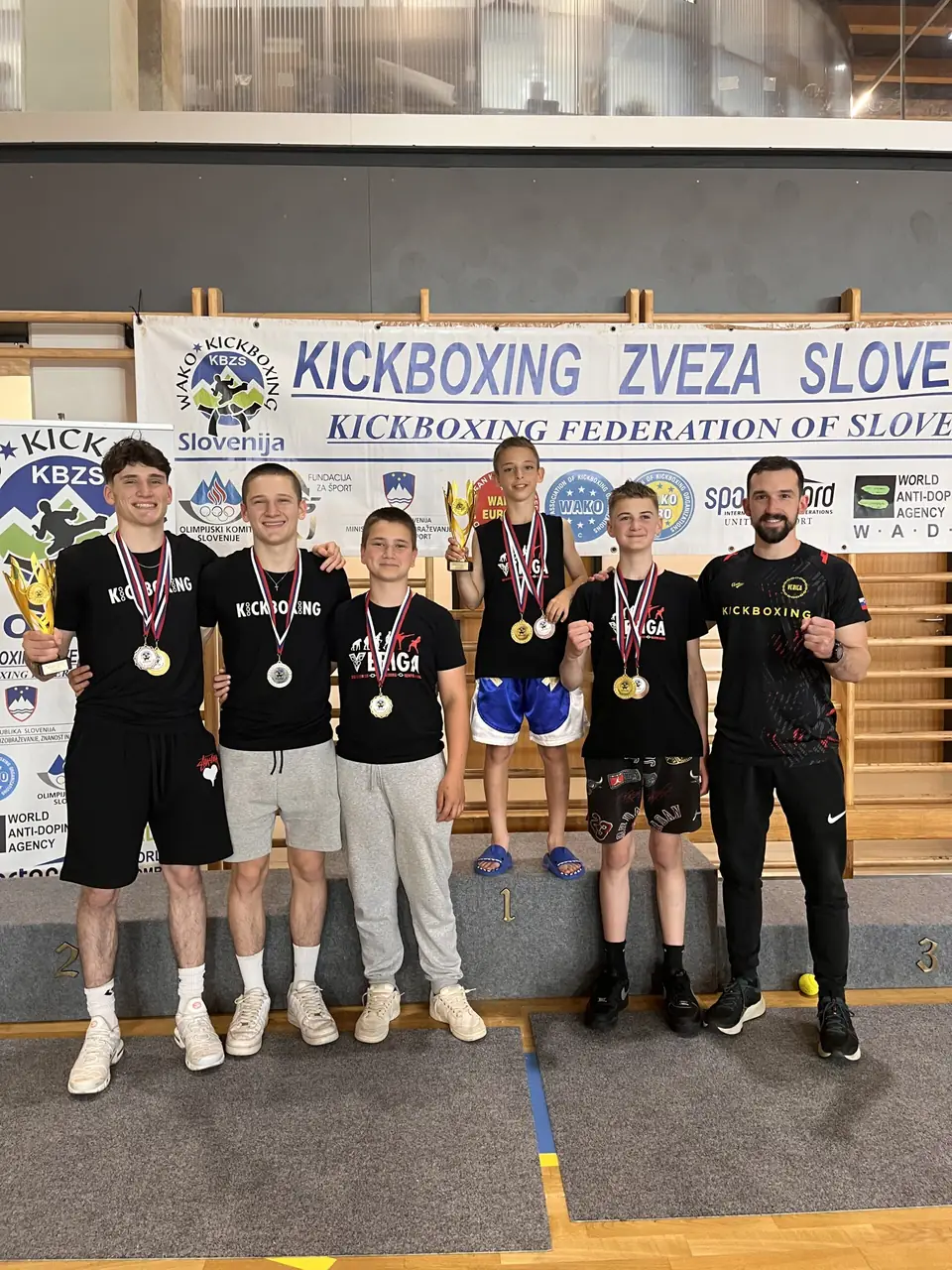 Skupina tekmovalcev z medaljami po tekmovanju v kickboxingu