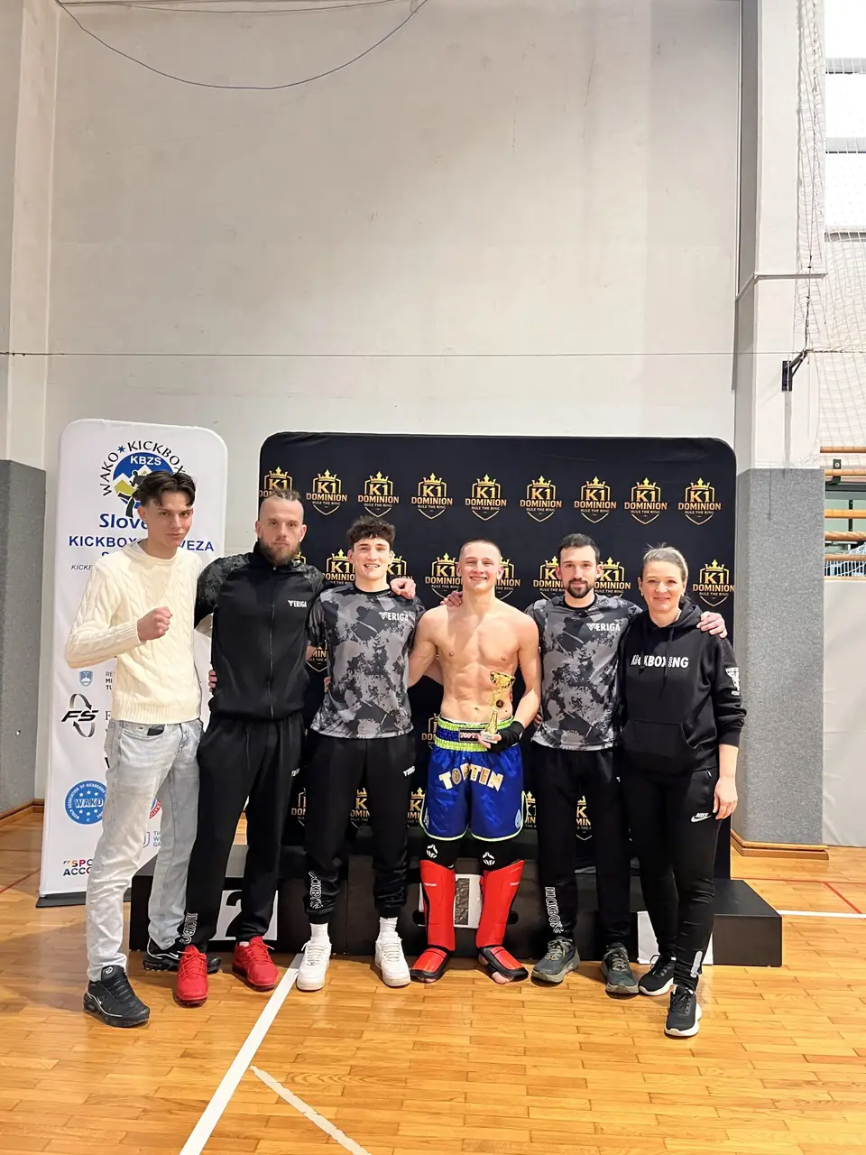 Tekmovalci in trenerji pred bannerjem kickbox tekmovanja